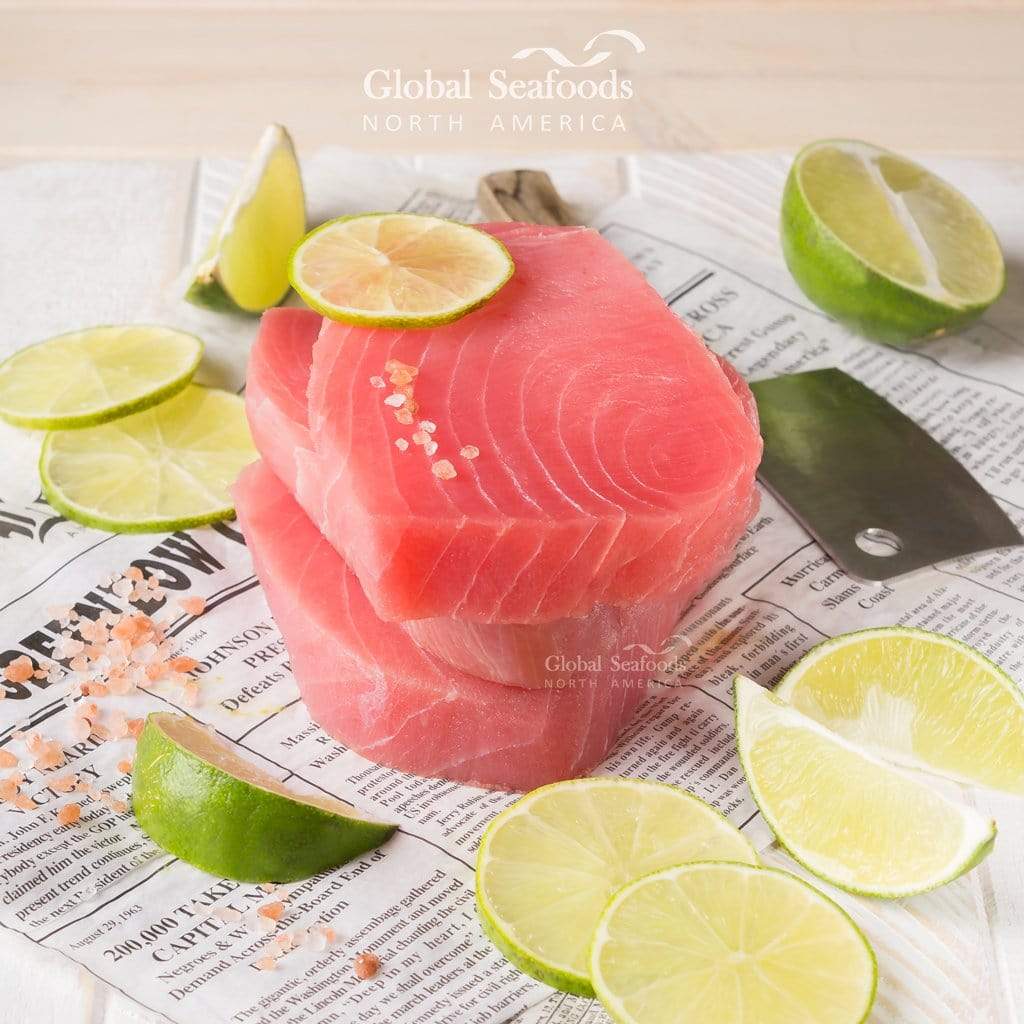 Raw tuna steaks with lime slices on a newspaper background, featuring Global Seafoods branding.